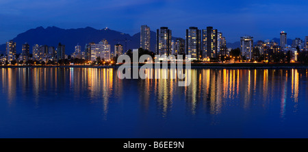 Panorama of West End Vancouver skyline city lights at twilight reflected in English Bay with Grouse Mountain British Columbia Canada Stock Photo