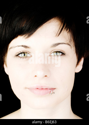 Smiling face of a dark-haired woman with a pierced lip Stock Photo