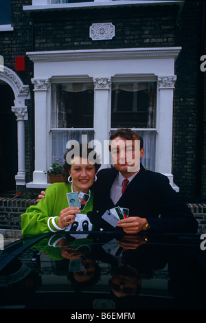 A Nineties couple pose outside their Clapham terraced house holding credit cards symbolising the credit boom of early 1990s Stock Photo