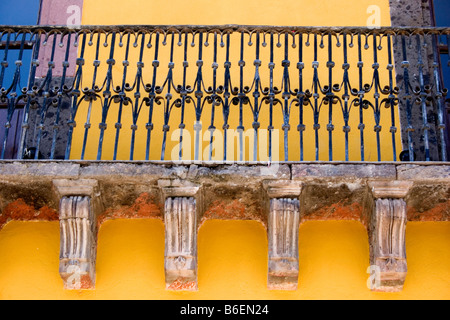 Balcony, window, and wrought iron on brightly colored yellow building in San Miguel de Allende, Mexico Stock Photo