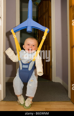 Happy Laughing Baby Boy Joshua Kailas Hudson Playing in Baby Bouncer Hanging in Doorway Stock Photo