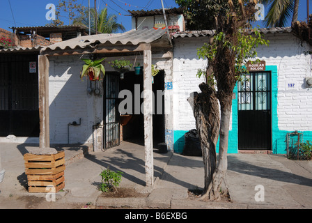 modest well-kept white-painted brick housefront with colorfully accented entry, flanked by humbler neighbor neighbour, Mexico Stock Photo