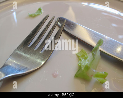 Knife and fork on empty plate after a meal Stock Photo