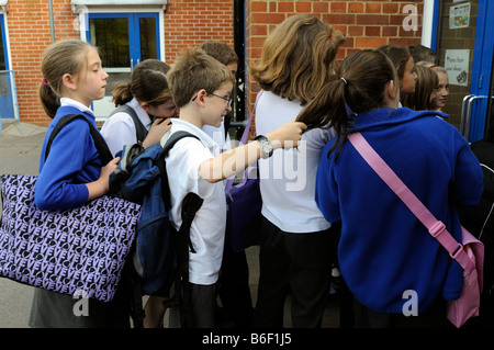 Boy bully pulling girls hair who is standing in line to enter primary ...