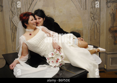 bride lying with her sister on grand piano Stock Photo