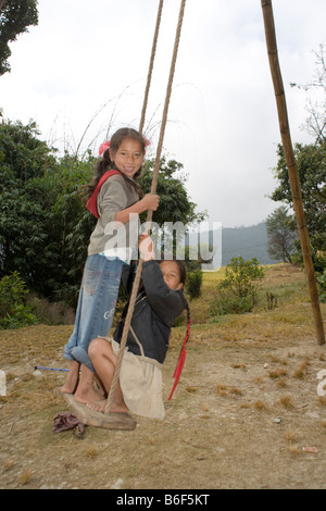 Two Nepalese children playing on a swing in the village of Dhampus in the Annapurna area of the Himalayas,Nepal Stock Photo
