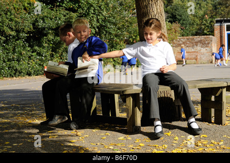 Schoolboys bully a schoolgirl classmate in the school playground Stock Photo