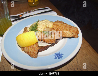 Traditional Danish Smørrebrød (smoerrebroed, open faced sandwich) with fish fillet and garnished with remoulade, dill and lemon Stock Photo
