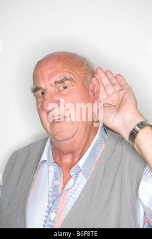 Elderly man acting, his hand at his ear Stock Photo