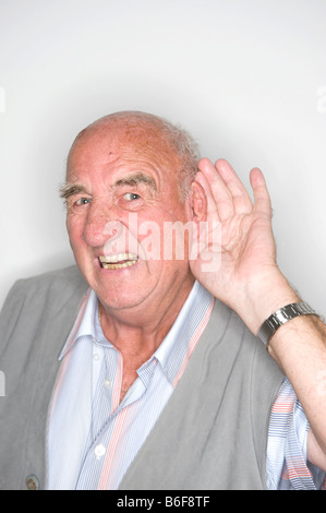 Elderly man acting, his hand at his ear Stock Photo