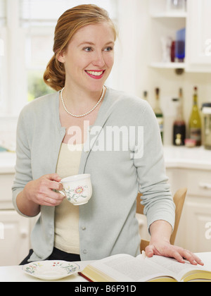 beautiful woman drinking a coffee in the kitchen, reading a book Stock Photo