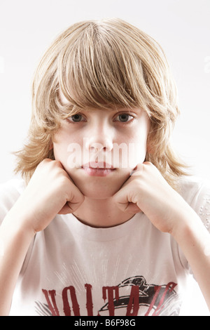 12 year-old boy looking into the camera, wresting his head on his hands Stock Photo