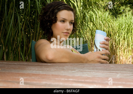 Girl holding a rolled-up magazine leaning against a wooden table Stock Photo