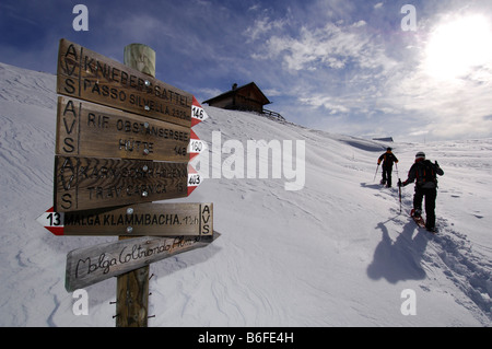 Sign post at Kniebergsattel or Knieberg Saddle, snowshoe hikers hiking to Alpe Nemes Mountain, High Puster Valley or Alto Puste Stock Photo