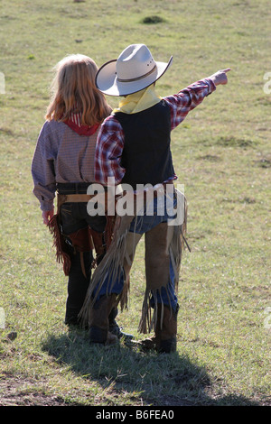 A young cowgirl and cowboy on the range pointing Stock Photo