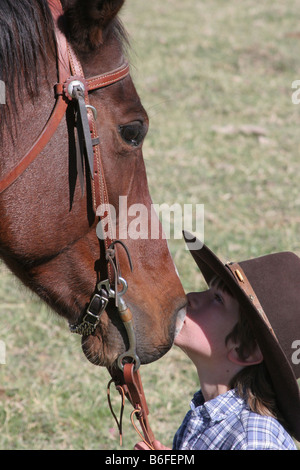A young cowboy kissing his horse on the ranch Stock Photo