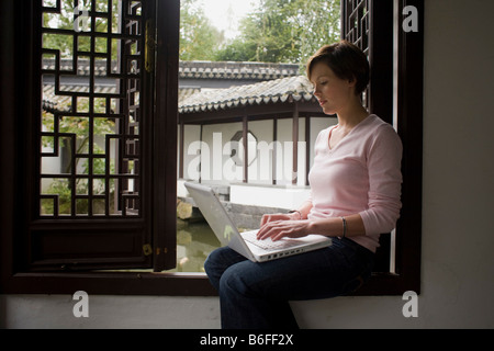 Young woman, student working on a laptop in a Chinese garden Stock Photo