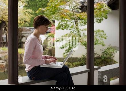 Young woman, student working on a laptop in a Chinese garden Stock Photo