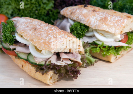 Onion baguette with salad, tomatoes, cucumber, roast pork, egg and mayonnaise Stock Photo