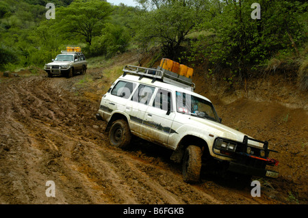 Two Toyota Landcruiser sliding down a muddy road near Jinka, Ethiopia, Africa Stock Photo