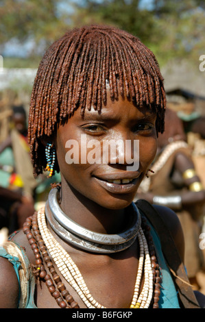 Young woman wearing red clay in her hair and earrings, portrait, at the markets in Dimeka, Ethiopia, Africa Stock Photo