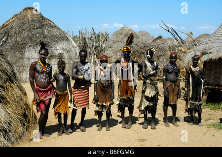 Group photo of a traditionally clothed villagers of the Karo people in front of their straw huts, Kolcho, South Omo Valley, Eth Stock Photo