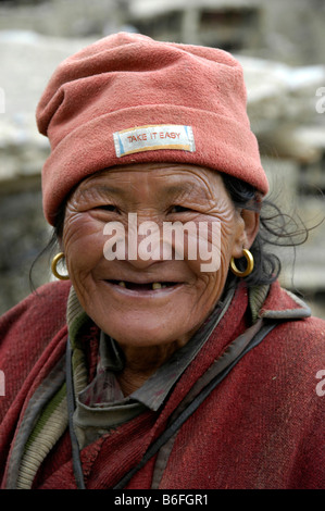 Portrait, smiling Tibetan woman wearing a hat labeled with the words, Take it Easy, Phu, Annapurna Region, Nepal, Asia Stock Photo