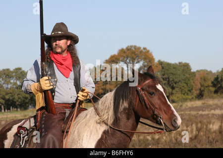 A cowboy on horseback with his rifle Stock Photo