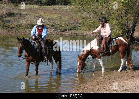 A cowboy and cowgirl watering their horses Stock Photo