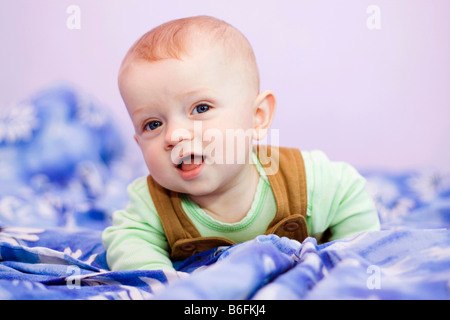 Smiling baby boy, 7 months old, on a bed Stock Photo