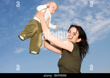 Happy mother, 32 years, holding her baby girl, 9 months, outside Stock Photo