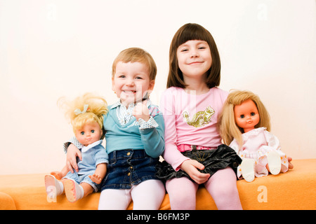 Little girls, 3 and 6 years, with dollies, indoors Stock Photo