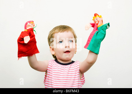 Little girl, 3 years, with two puppets Stock Photo