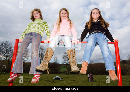 Three little girls sitting on a cross-bar, 9, 11 and 9 years