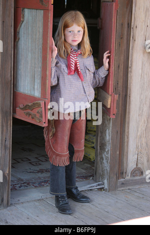 A young cowgirl walking out of a saloon bar in an old west town Stock Photo