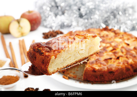 Christmas apple pie with fresh apples, cinnamon, sticks of cinnamon and sugar on a pie server Stock Photo