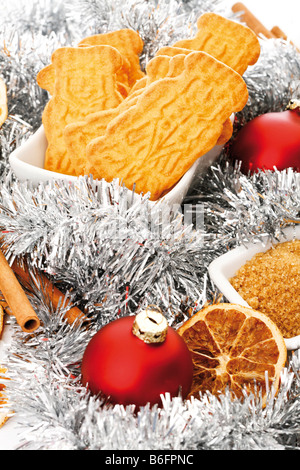 Spiced biscuits in a white bowl and christmas decorations, cinnamon sticks, orange slices and christmas tree balls Stock Photo