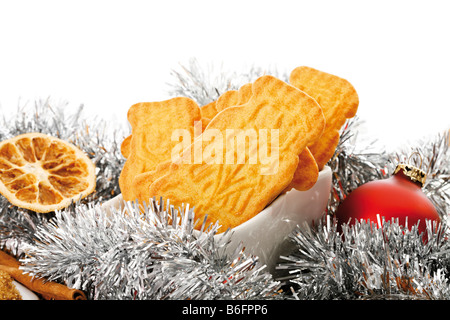 Spiced biscuits in a white bowl, christmas decorations, cinnamon sticks, orange slices and christmas tree balls Stock Photo