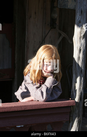 A young cowgirl looking bored in an old west town Stock Photo