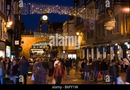UK Cheshire Chester Eastgate Street Jubilee clock Christmas lighting above shoppers at dusk Stock Photo