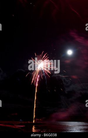 Firework display light show rocket explosion spread in black sky Full moon Newport Pembrokeshire coast. Vertical 89027 Fireworks Stock Photo