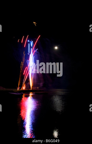 Firework display light show rocket explosion spread in black sky Full moon Newport Pembrokeshire coast. Vertical 88999 Fireworks Stock Photo