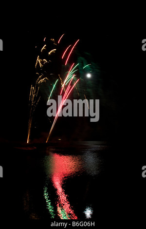 Firework display light show rocket explosion spread in black sky Full moon Newport Pembrokeshire coast. Vertical 89003 Fireworks Stock Photo