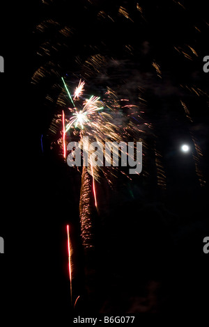 Firework display light show rocket explosion spread in black sky Full moon Newport Pembrokeshire coast. Vertical 89019 Fireworks Stock Photo