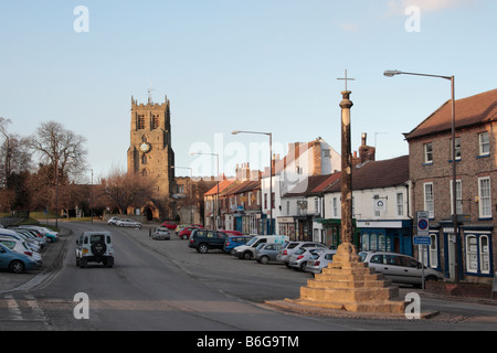 Bedale high street with 14th century market cross and St Gregory s Saxon church at end of street North Yorkshire England Stock Photo