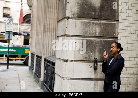 a young woman smoking a cigarette outside her office in The City of London Stock Photo