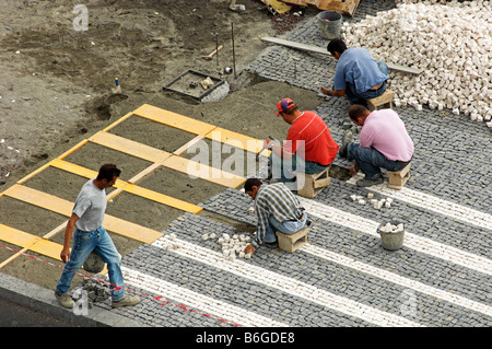 Workmen laying decorative cobblestone pavement Stock Photo