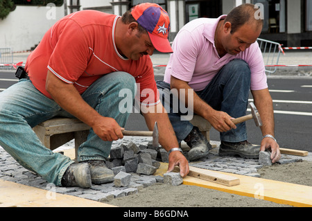 Workmen laying decorative cobblestone pavement Stock Photo
