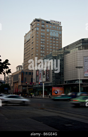 Early morning rush hour in downtown cars in motion blur with big shopping mall and Legend Holiday Hotel in background Stock Photo