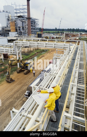 Construction engineers at recycling facility, pipeline leading into factory, Stock Photo